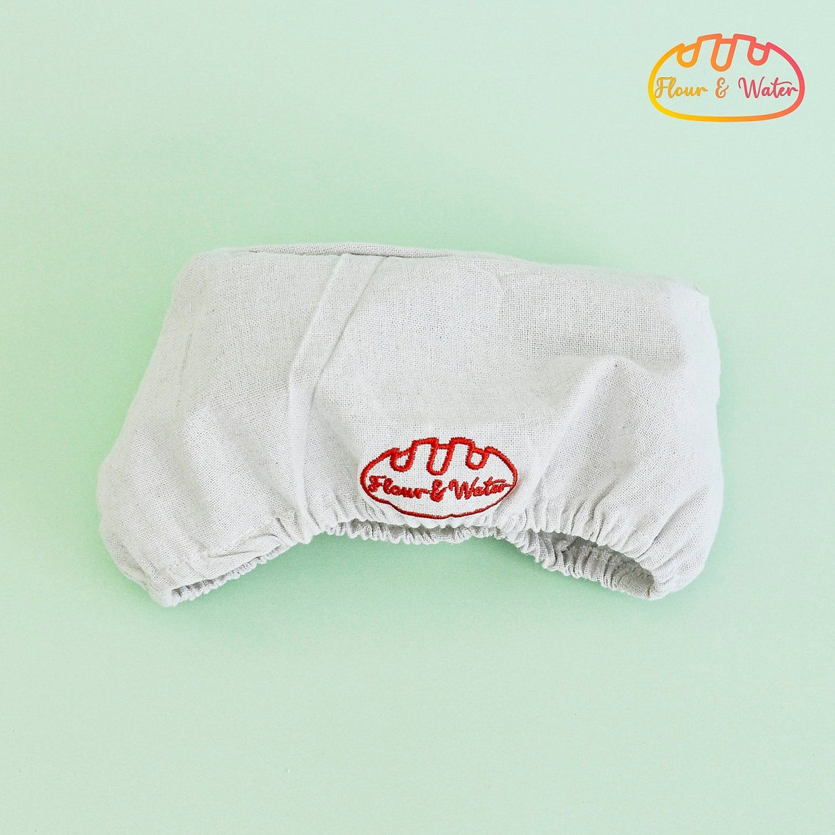 Oval cloth banneton liner with elasticated edge and embroidered logo