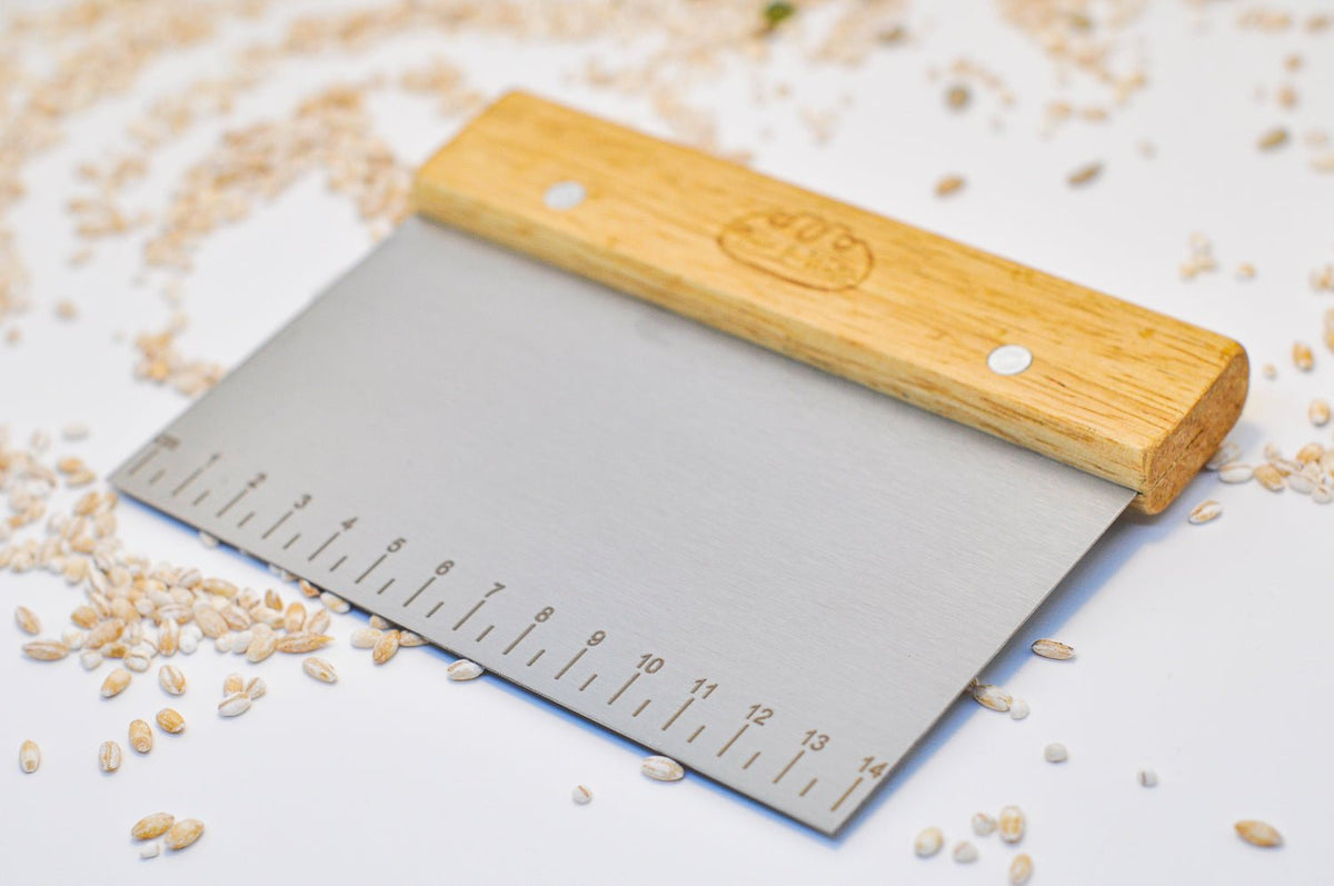 Bench scraper with ruler markings lying on a bench with grains