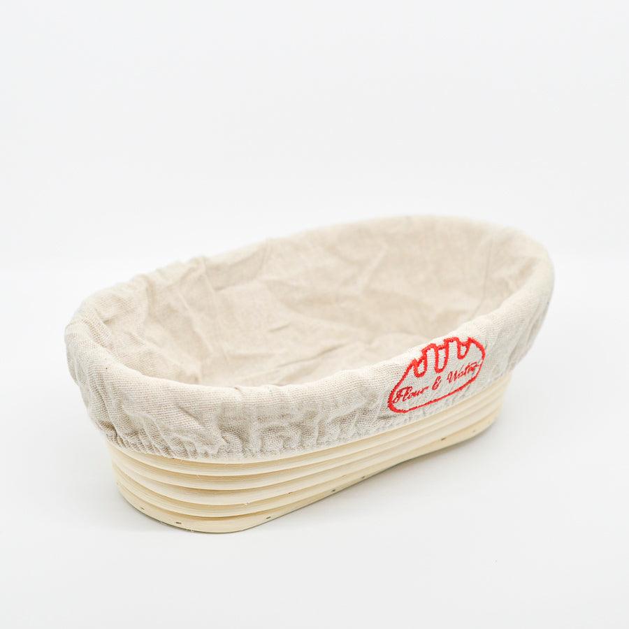 Oval rattan banneton with cloth liner on a white background