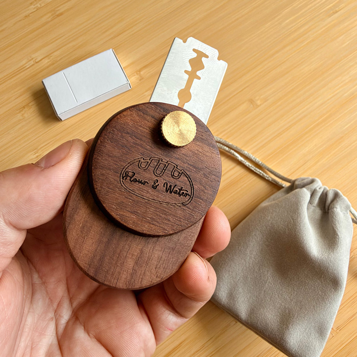 Compact walnut swivel bread lame held in hand with blade extended