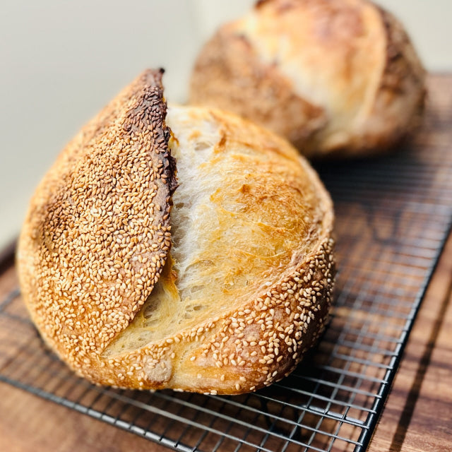 Loaf of bread with sesame seeds on a cooling rack