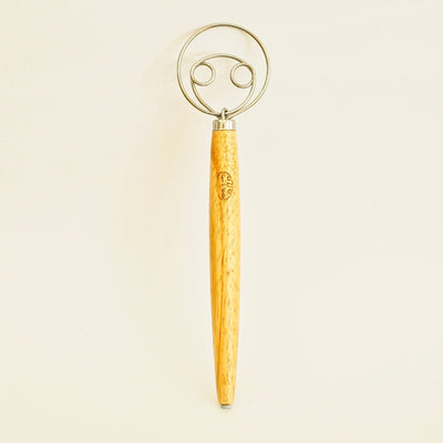 Wooden Danish dough whisk with steel loops, standing upright