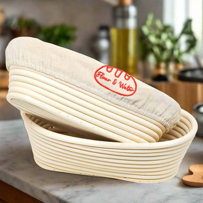Two oval rattan bannetons stacked, one with a Flour & Water cloth liner, on a kitchen bench